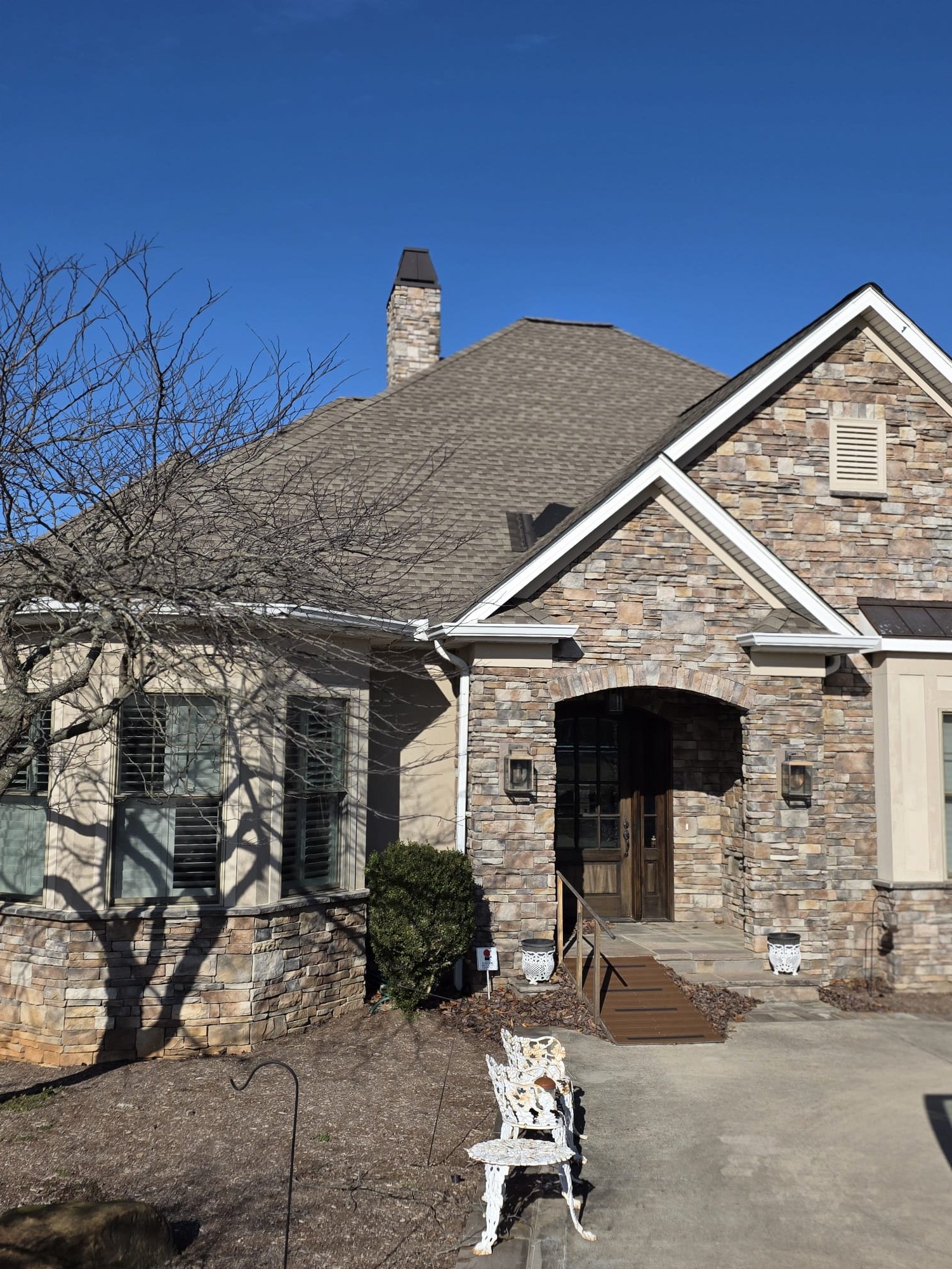 Architectural shingles neatly aligned around a stone chimney.